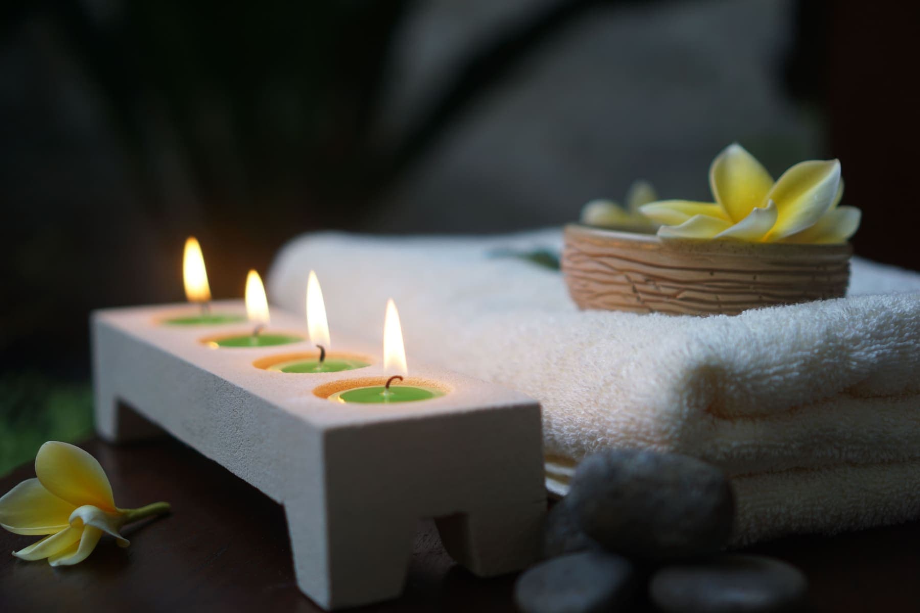 Velas encendidas junto a toallas blancas y una flor